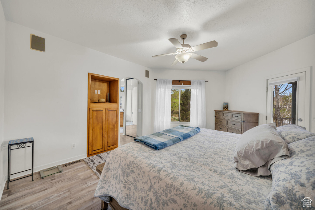 Bedroom featuring ceiling fan, multiple windows, access to exterior, and light hardwood / wood-style floors