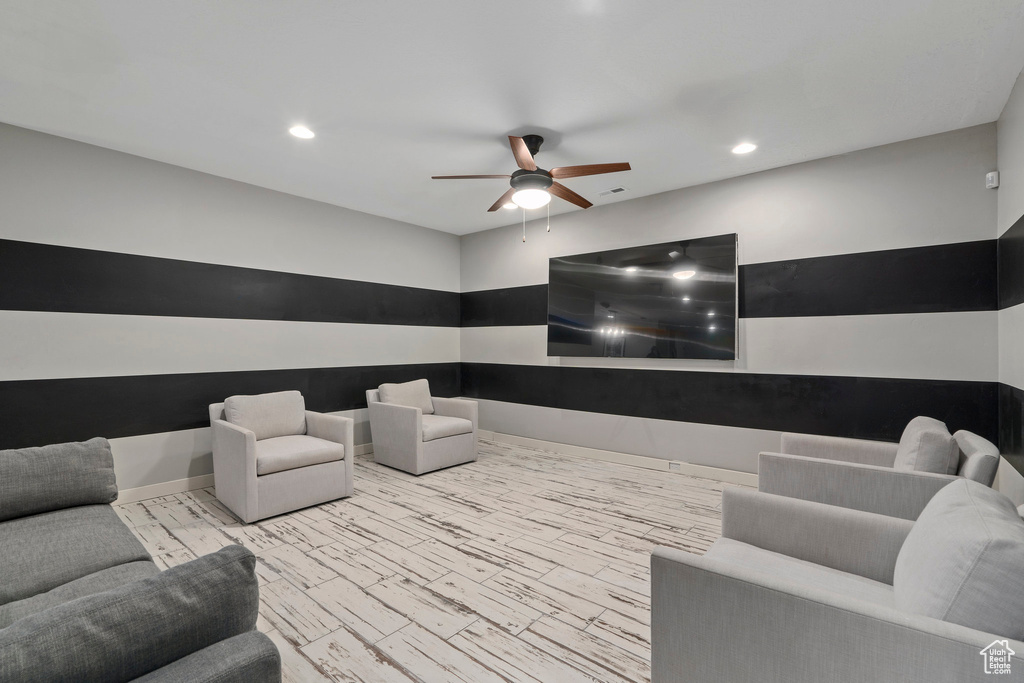 Cinema room with ceiling fan and light hardwood / wood-style floors