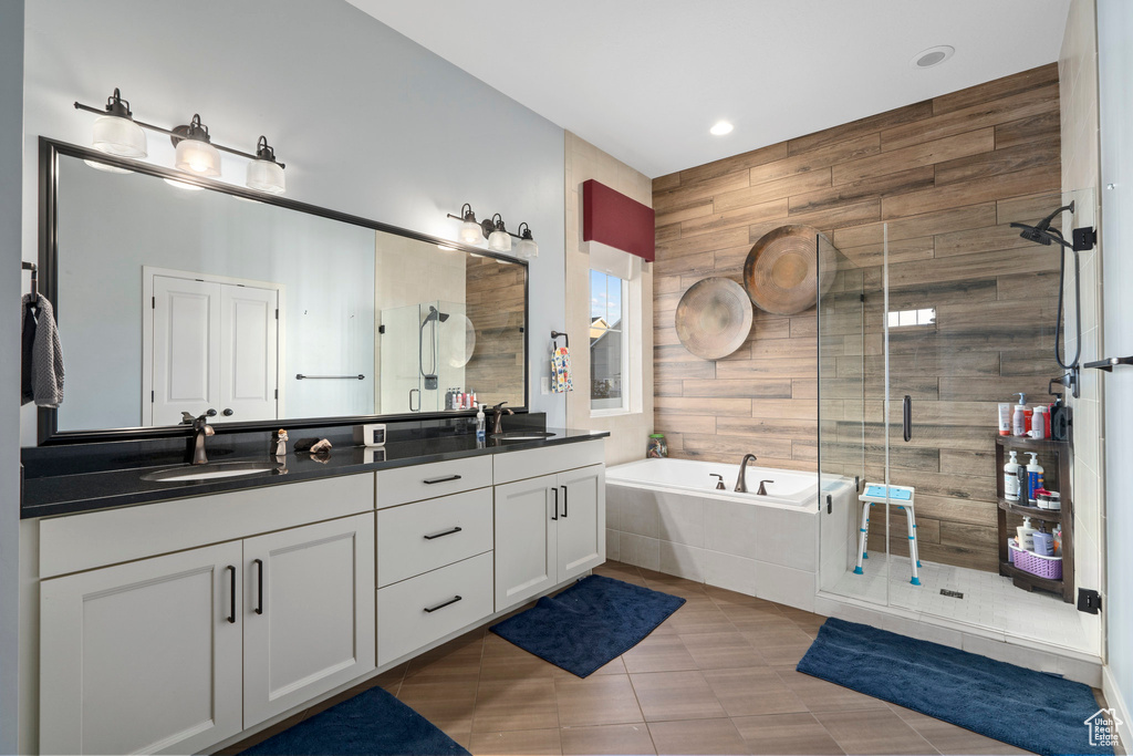 Bathroom featuring wood walls, plus walk in shower, tile flooring, double sink, and large vanity