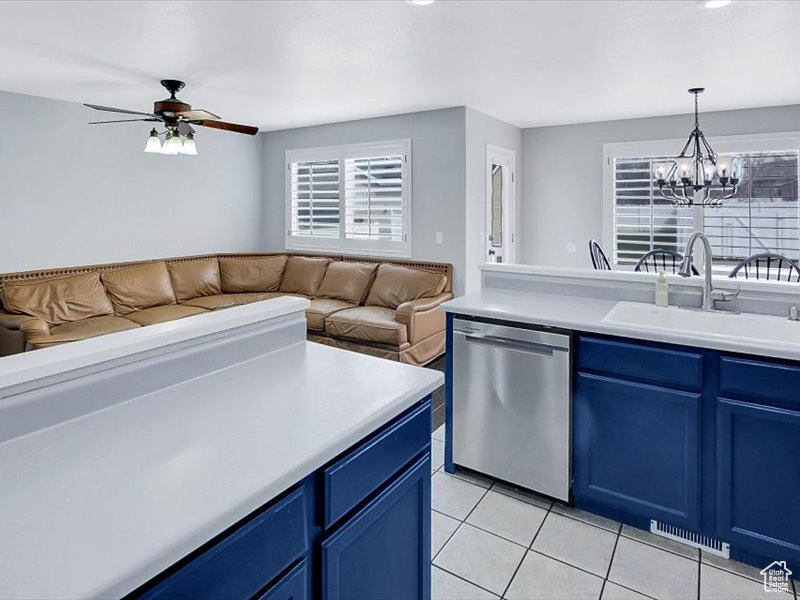 Kitchen featuring hanging light fixtures, blue cabinets, sink, stainless steel dishwasher, and ceiling fan with notable chandelier