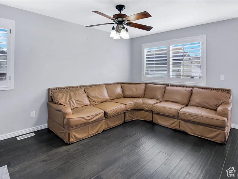 Unfurnished living room featuring ceiling fan and dark wood-type flooring