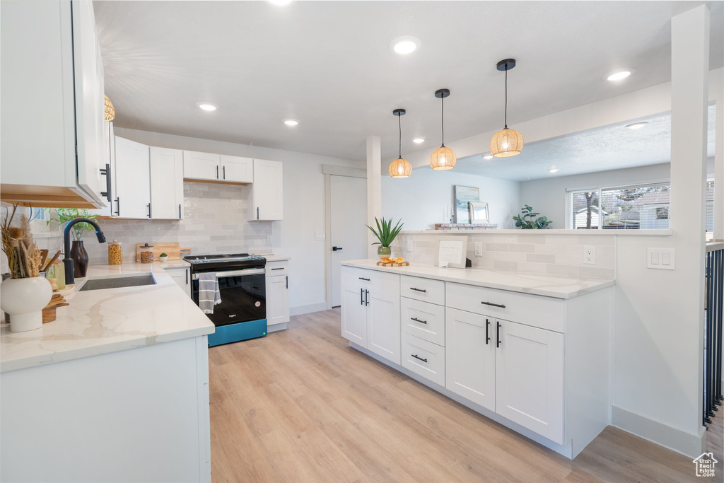 Kitchen with backsplash, stainless steel range with electric cooktop, and white cabinets