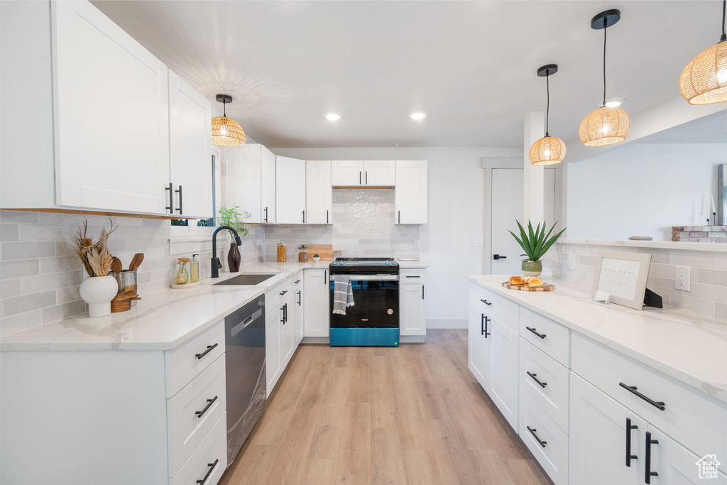 Kitchen with white cabinets, backsplash, stainless steel range oven, light wood-type flooring, and hanging light fixtures