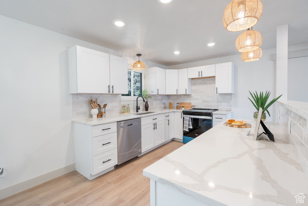 Kitchen with hanging light fixtures, white cabinetry, and appliances with stainless steel finishes