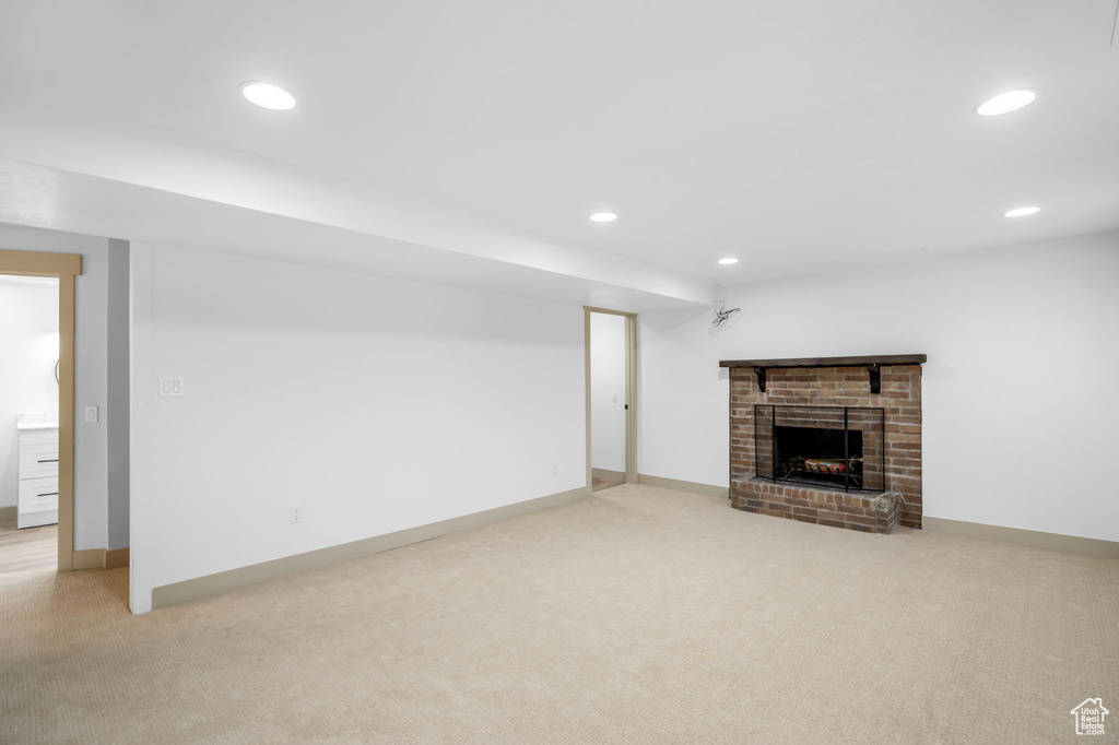 Unfurnished living room featuring light carpet and a fireplace