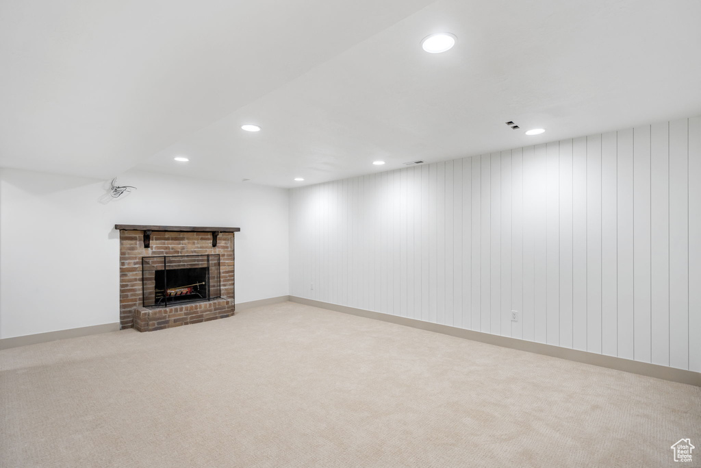 Unfurnished living room with light colored carpet and a fireplace