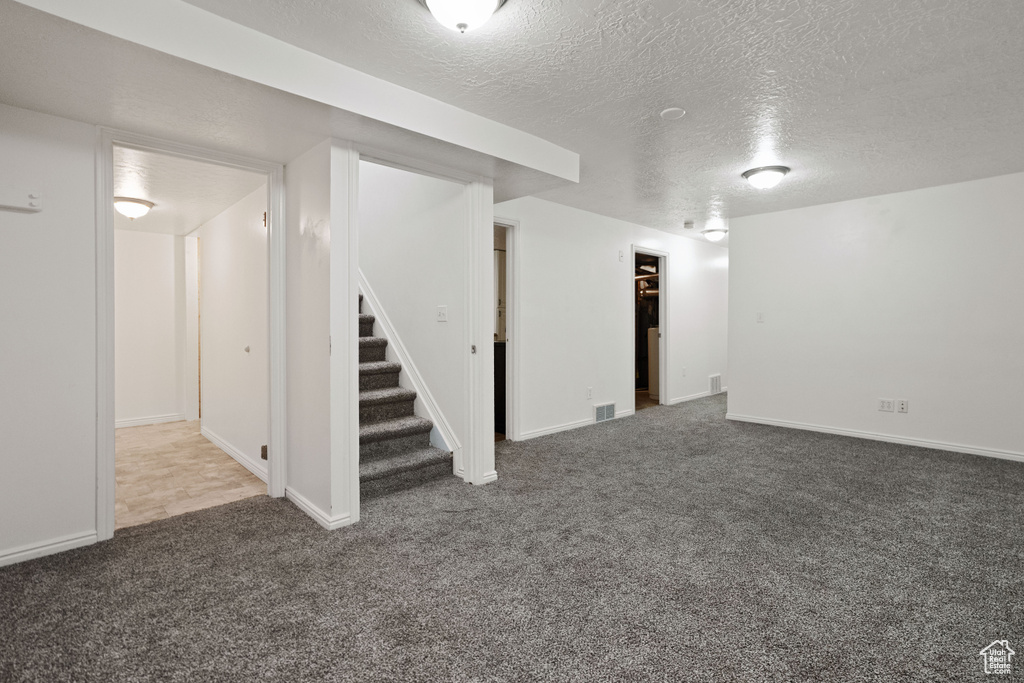 Basement featuring a textured ceiling and carpet flooring