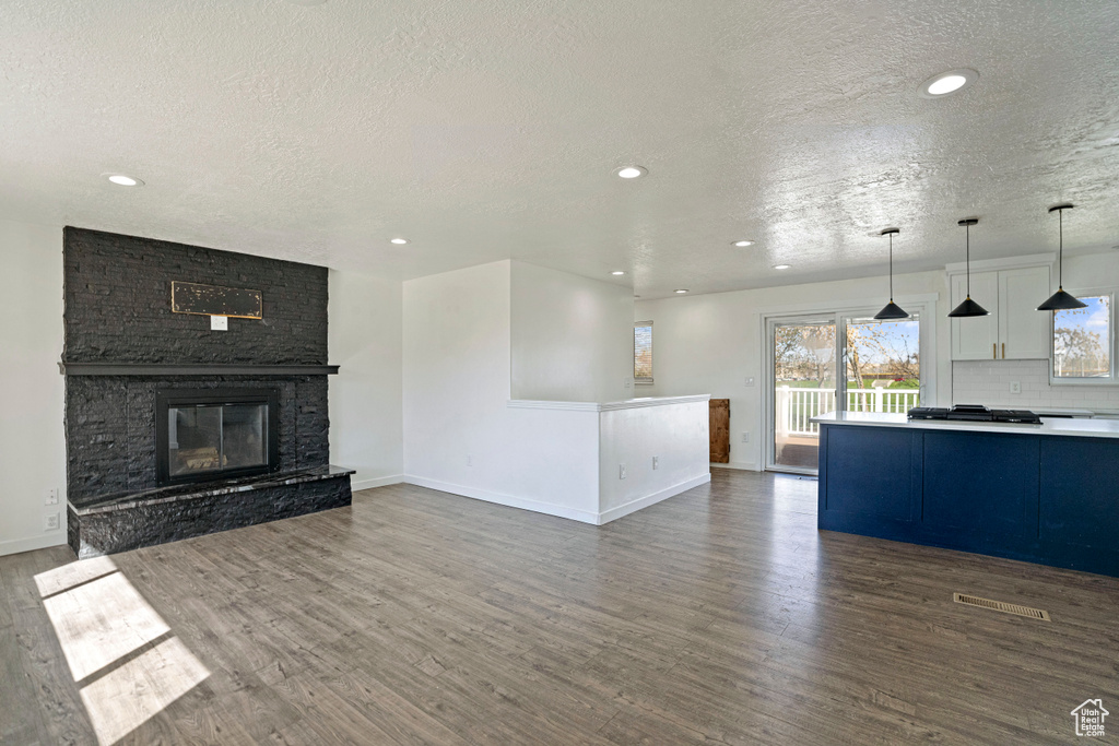 Unfurnished living room featuring dark hardwood / wood-style flooring, a fireplace, and a textured ceiling