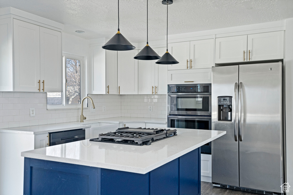 Kitchen with backsplash, white cabinetry, and appliances with stainless steel finishes