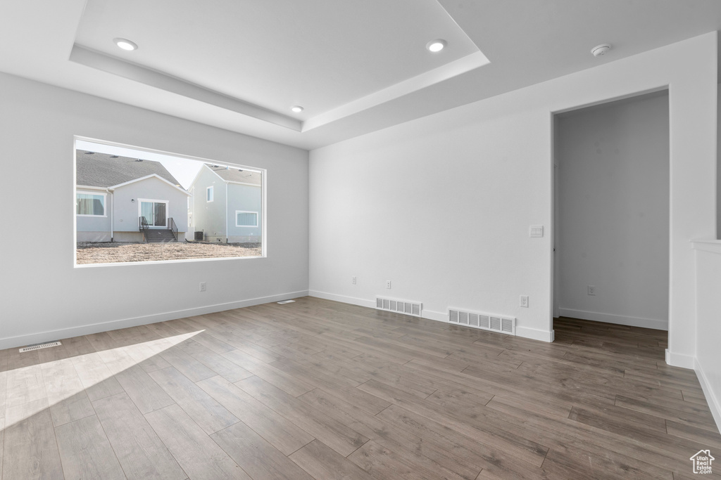 Unfurnished room with hardwood / wood-style flooring and a raised ceiling