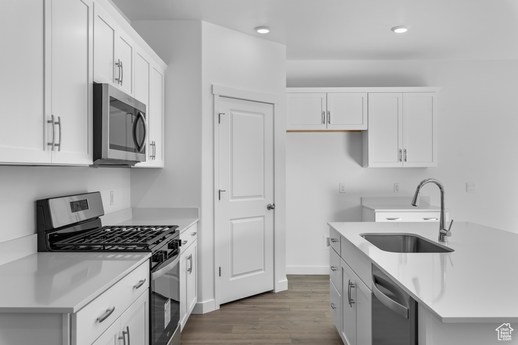 Kitchen featuring appliances with stainless steel finishes, sink, dark wood-type flooring, and white cabinets