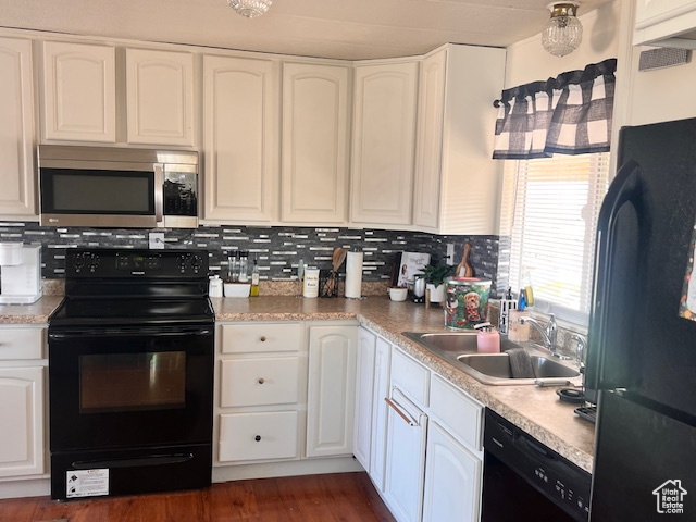 Kitchen featuring dark wood-type flooring, white cabinets, black appliances, backsplash, and sink
