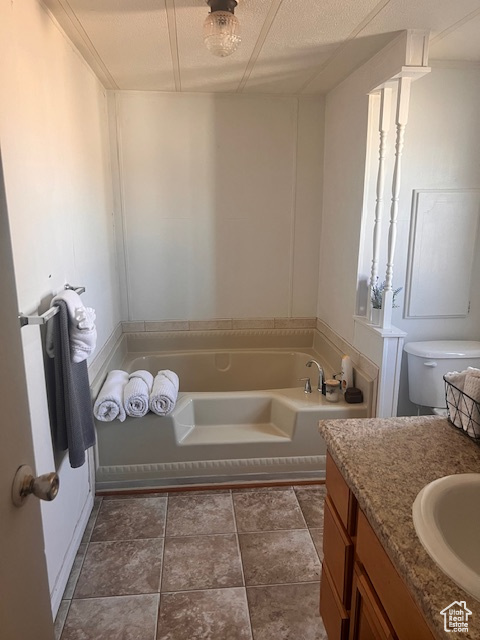 Bathroom featuring tile floors, a textured ceiling, toilet, vanity, and a bathing tub