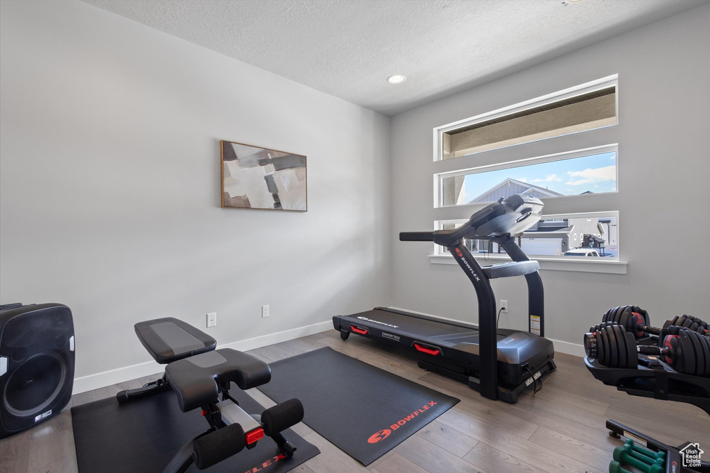 Workout room featuring a textured ceiling and light wood-type flooring