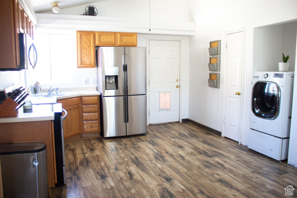 Kitchen with washer / clothes dryer, dark hardwood / wood-style flooring, stainless steel appliances, and sink