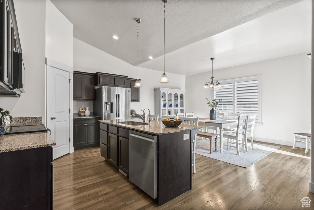 Kitchen with appliances with stainless steel finishes, hanging light fixtures, dark wood-type flooring, a notable chandelier, and sink