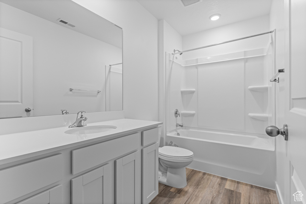 Full bathroom with toilet, shower / tub combination, hardwood / wood-style floors, and vanity