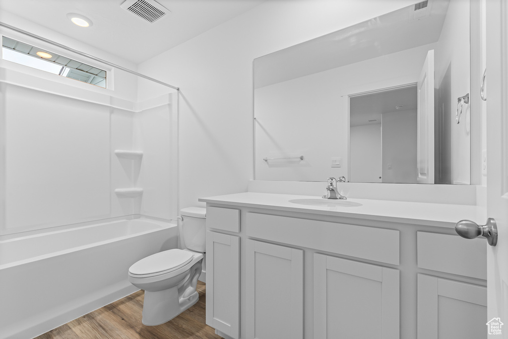 Full bathroom with toilet, shower / tub combination, hardwood / wood-style flooring, and vanity