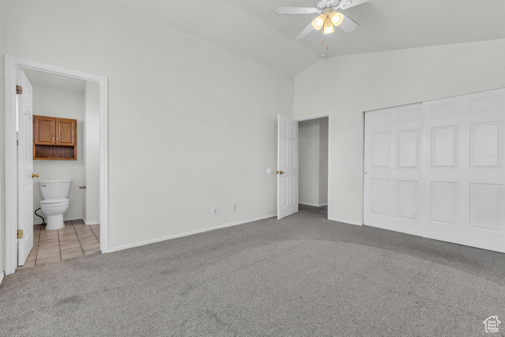 Unfurnished bedroom featuring light colored carpet, connected bathroom, ceiling fan, and vaulted ceiling