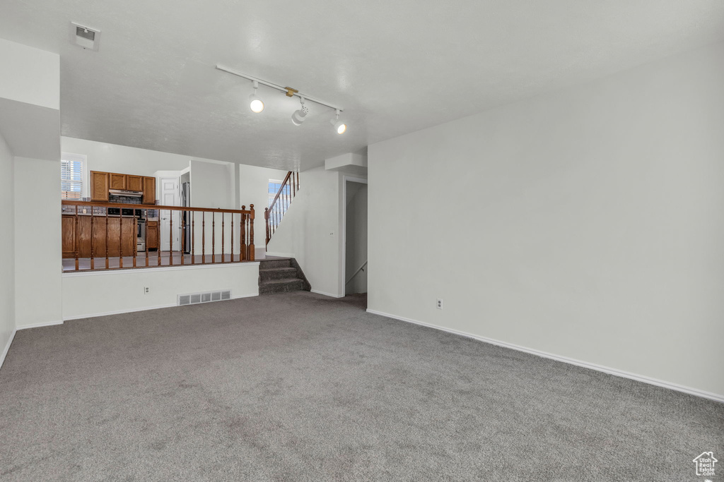 Unfurnished living room featuring carpet flooring and rail lighting