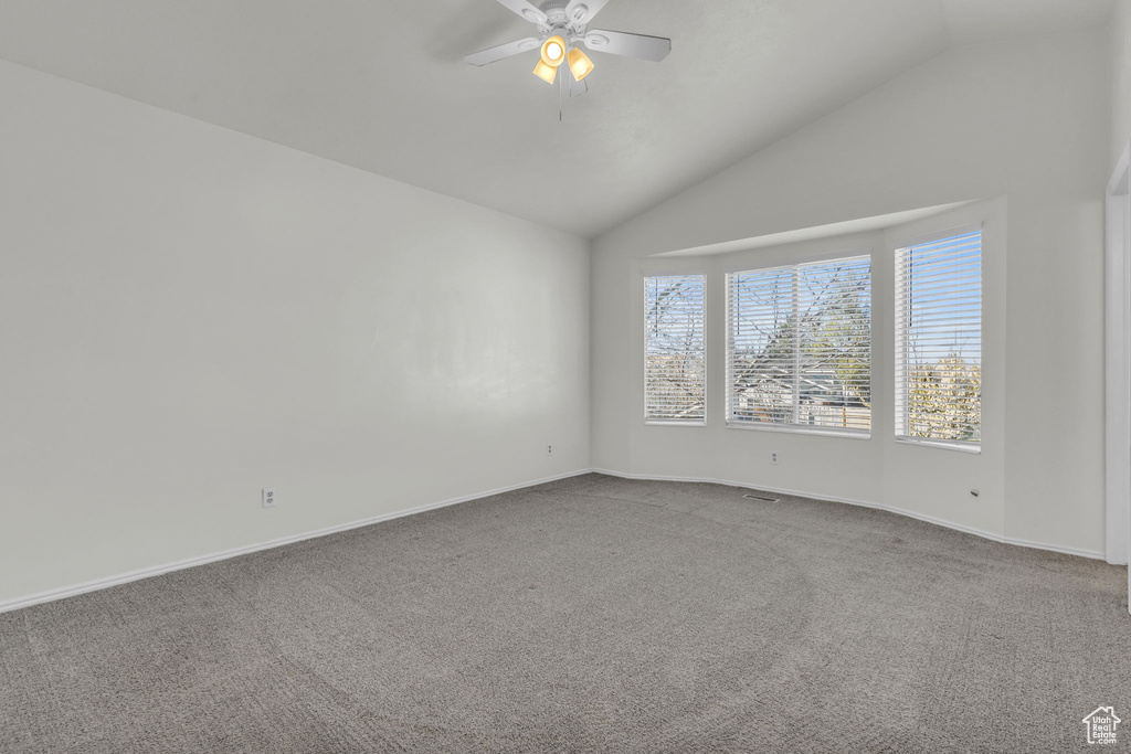 Carpeted empty room featuring lofted ceiling and ceiling fan