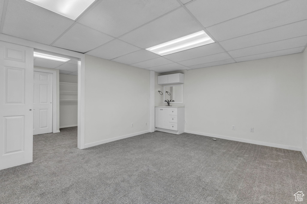 Basement featuring a drop ceiling and light colored carpet