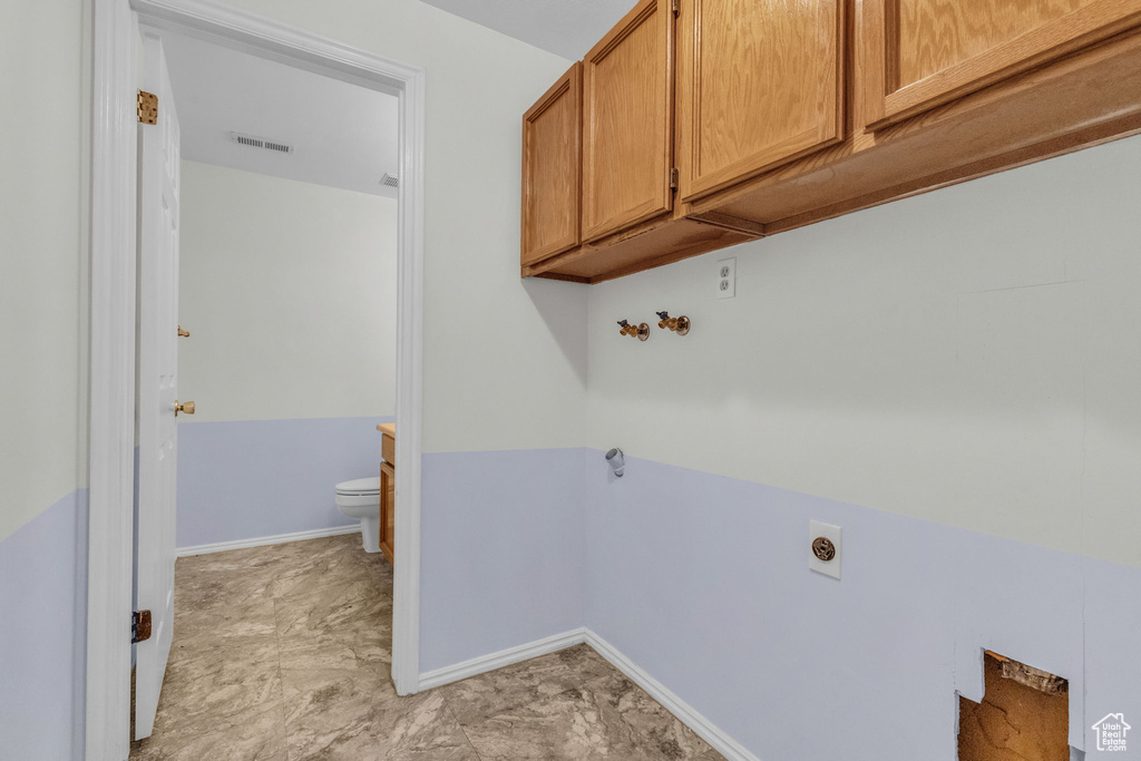 Washroom featuring cabinets, light tile flooring, and electric dryer hookup