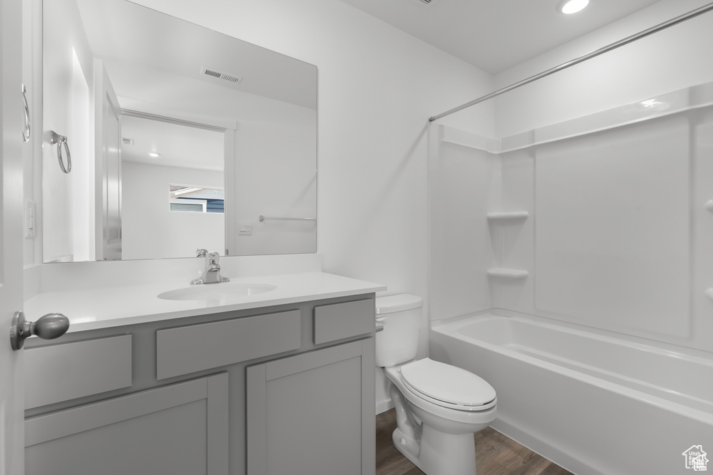 Full bathroom with vanity, shower / tub combination, hardwood / wood-style floors, and toilet