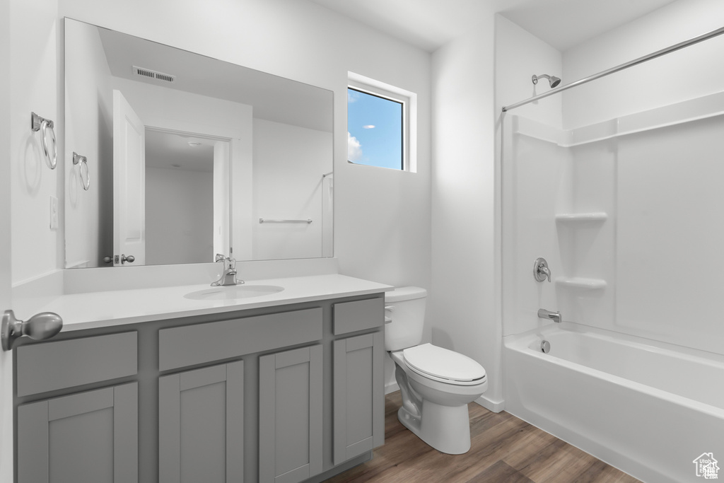 Full bathroom with washtub / shower combination, toilet, hardwood / wood-style floors, and vanity