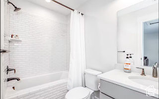 Full bathroom featuring toilet, large vanity, and shower / bathtub combination with curtain