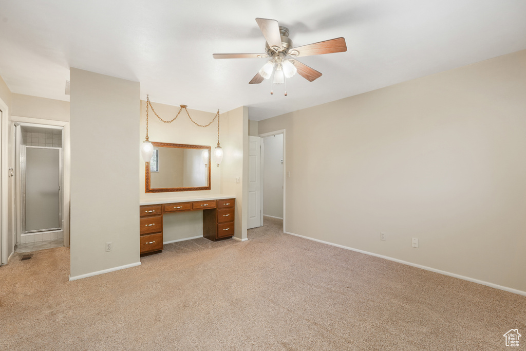 Unfurnished bedroom featuring ceiling fan, light carpet, and ensuite bath