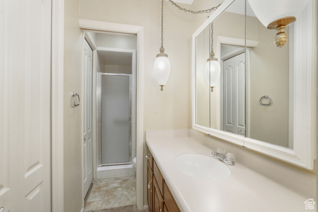 Bathroom with walk in shower, tile floors, toilet, and vanity with extensive cabinet space