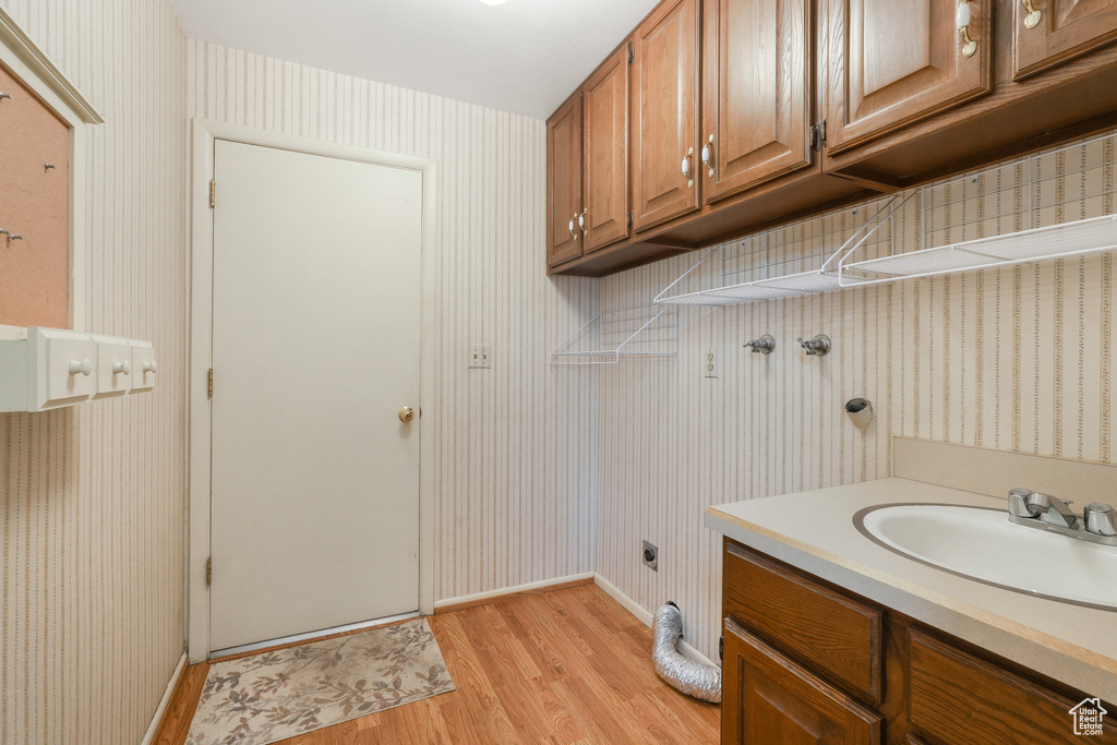 Interior space with hookup for an electric dryer, light hardwood / wood-style flooring, cabinets, and sink