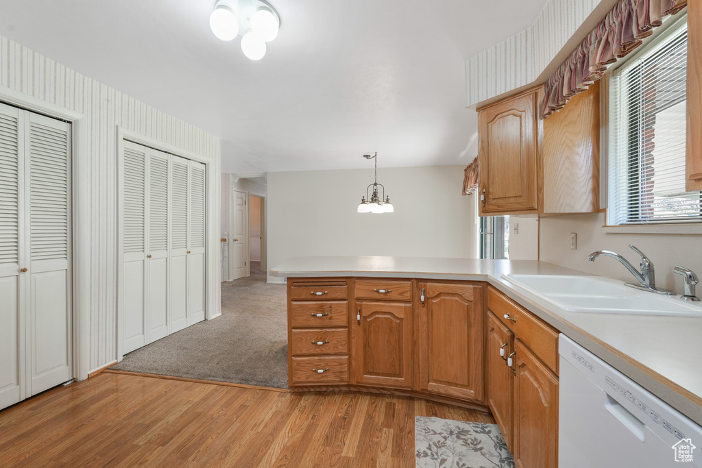 Kitchen with light carpet, sink, kitchen peninsula, dishwasher, and hanging light fixtures
