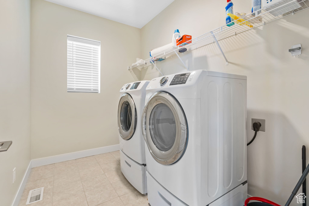 Laundry room featuring light tile floors, washing machine and dryer, and hookup for an electric dryer