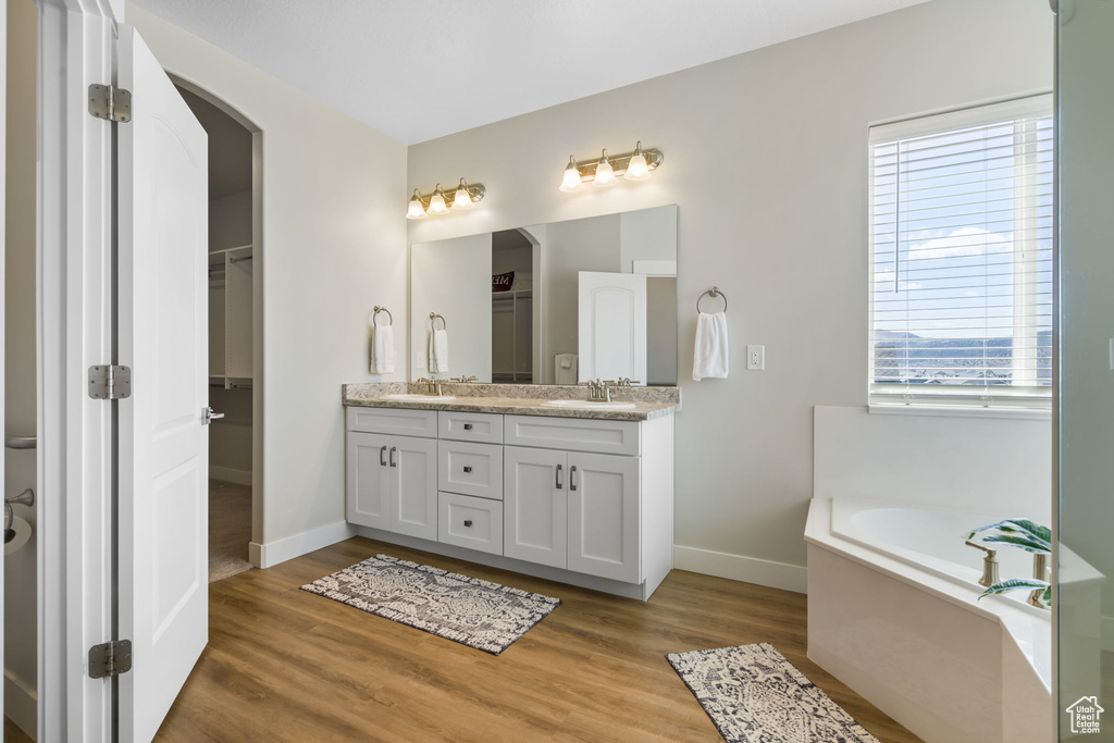 Bathroom featuring dual vanity, a bathing tub, and hardwood / wood-style flooring