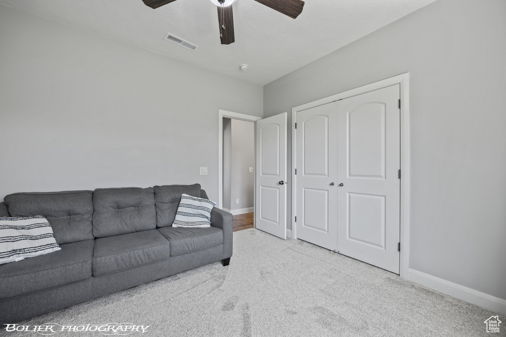 Living room with ceiling fan and light carpet