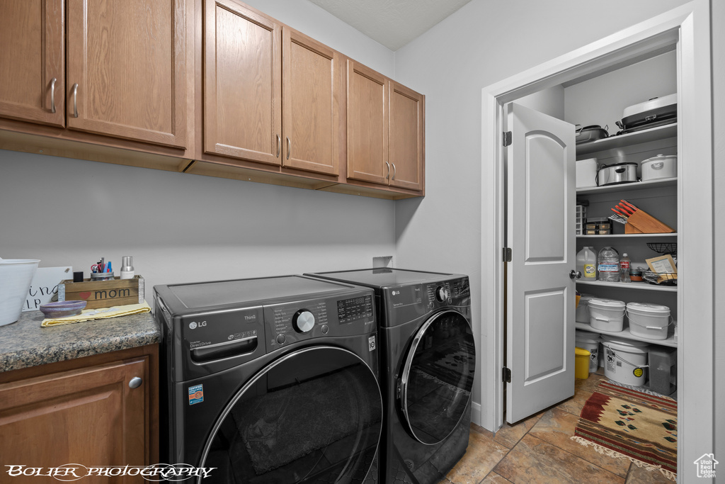 Washroom with light tile floors, independent washer and dryer, and cabinets