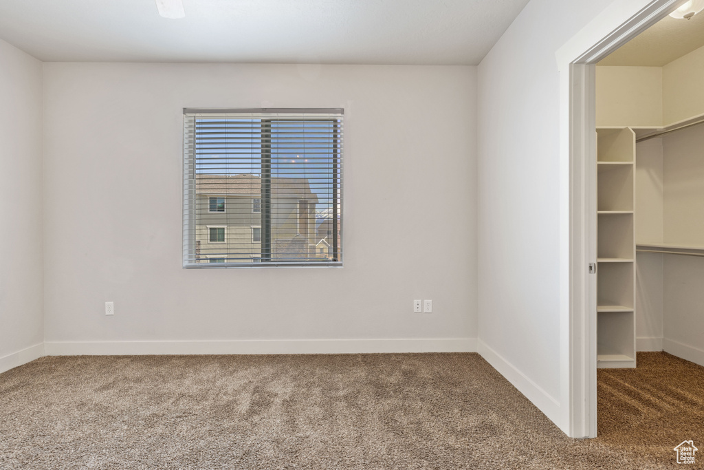 Unfurnished bedroom with a closet, a walk in closet, and carpet floors