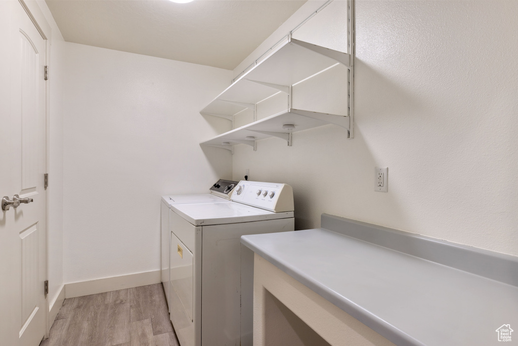 Laundry room with washer and dryer and light hardwood / wood-style flooring