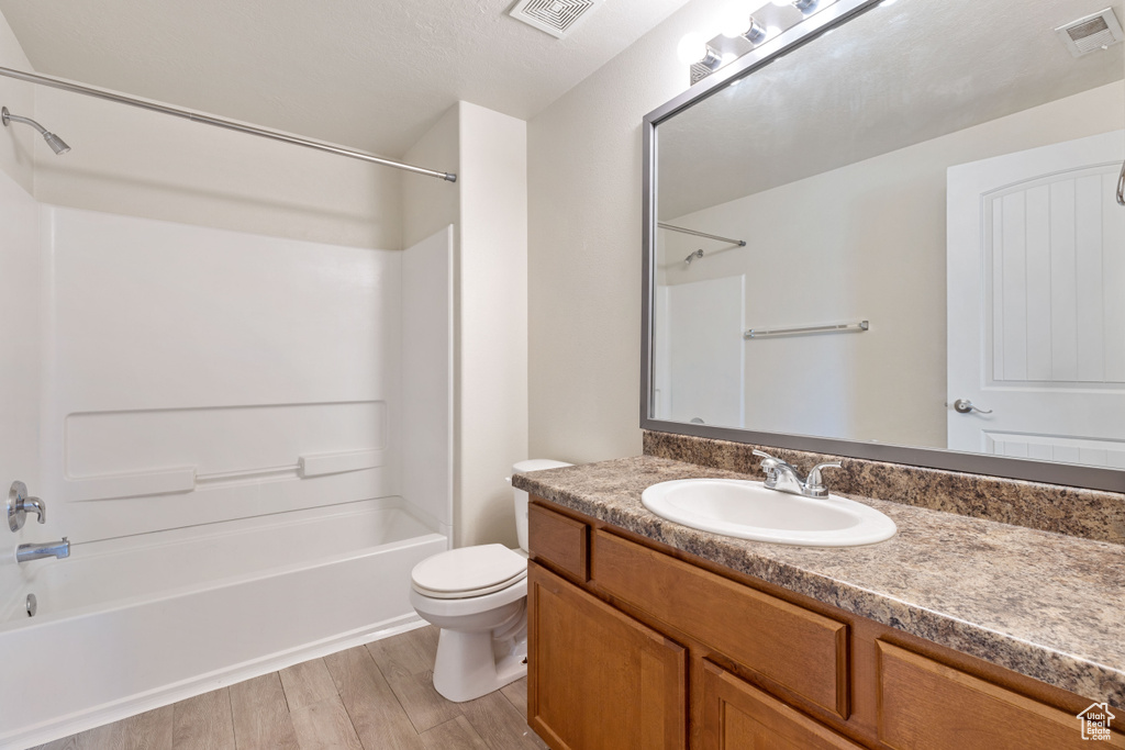 Full bathroom with a textured ceiling, toilet, hardwood / wood-style flooring, vanity, and shower / bathing tub combination