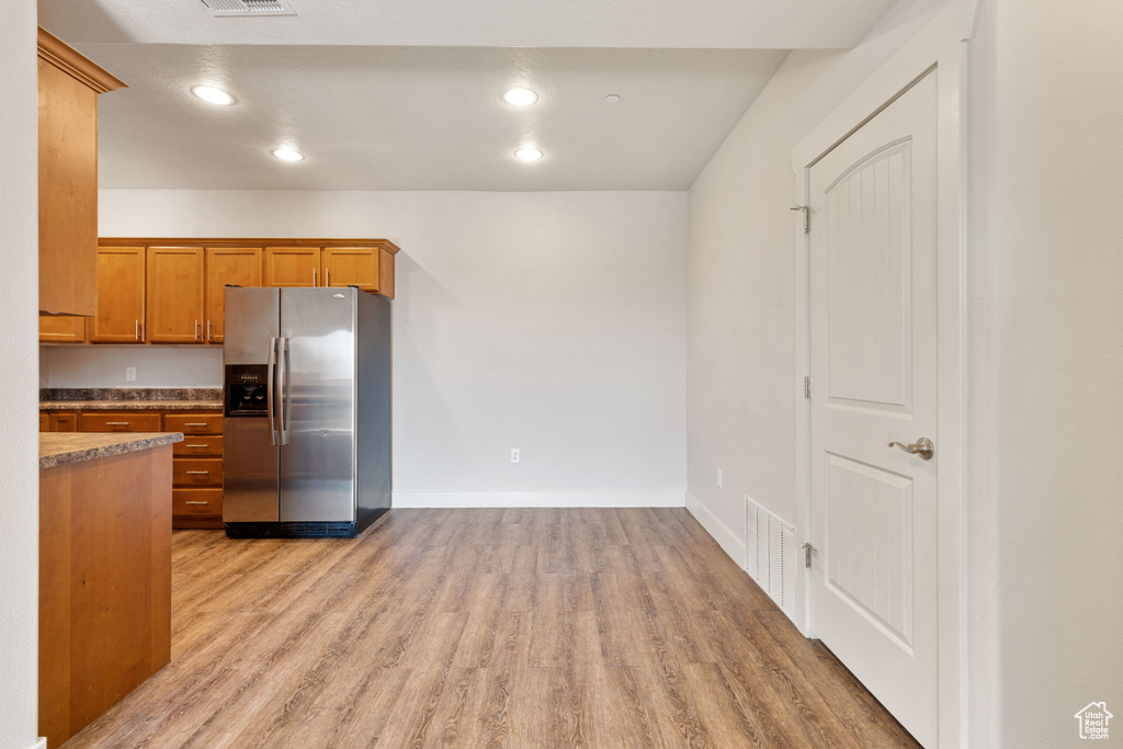 Kitchen with light hardwood / wood-style floors and stainless steel fridge with ice dispenser