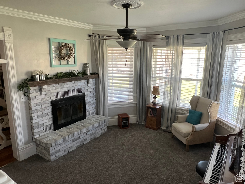 Living room with dark carpet, crown molding, ceiling fan, and a fireplace