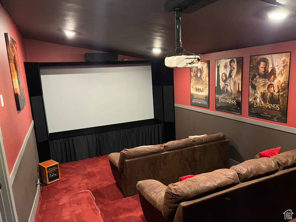 Carpeted home theater room featuring vaulted ceiling