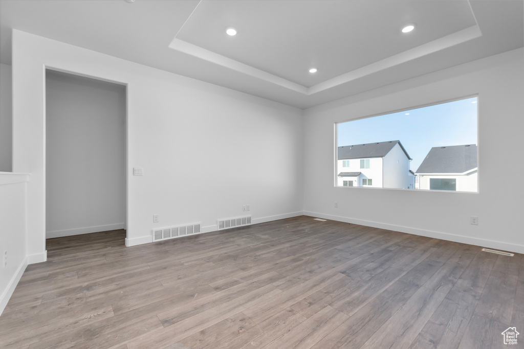 Unfurnished room with hardwood / wood-style floors and a tray ceiling