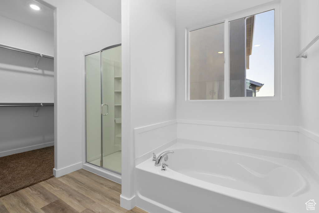 Bathroom with shower with separate bathtub, a wealth of natural light, and wood-type flooring
