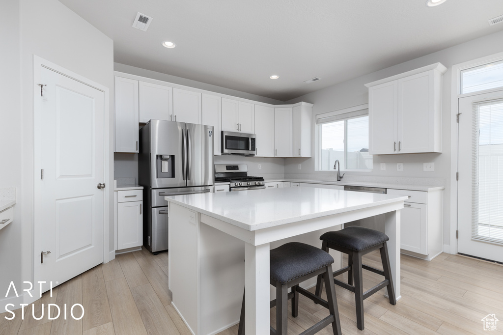 Kitchen featuring appliances with stainless steel finishes, white cabinetry, a kitchen island, and a healthy amount of sunlight