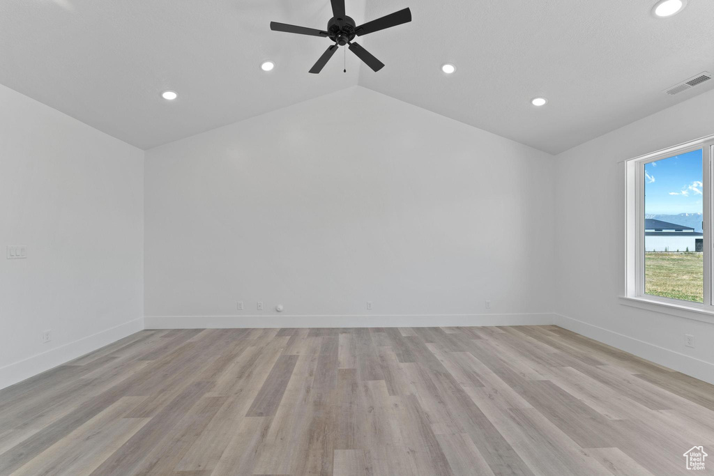 Empty room featuring ceiling fan, lofted ceiling, and light hardwood / wood-style floors