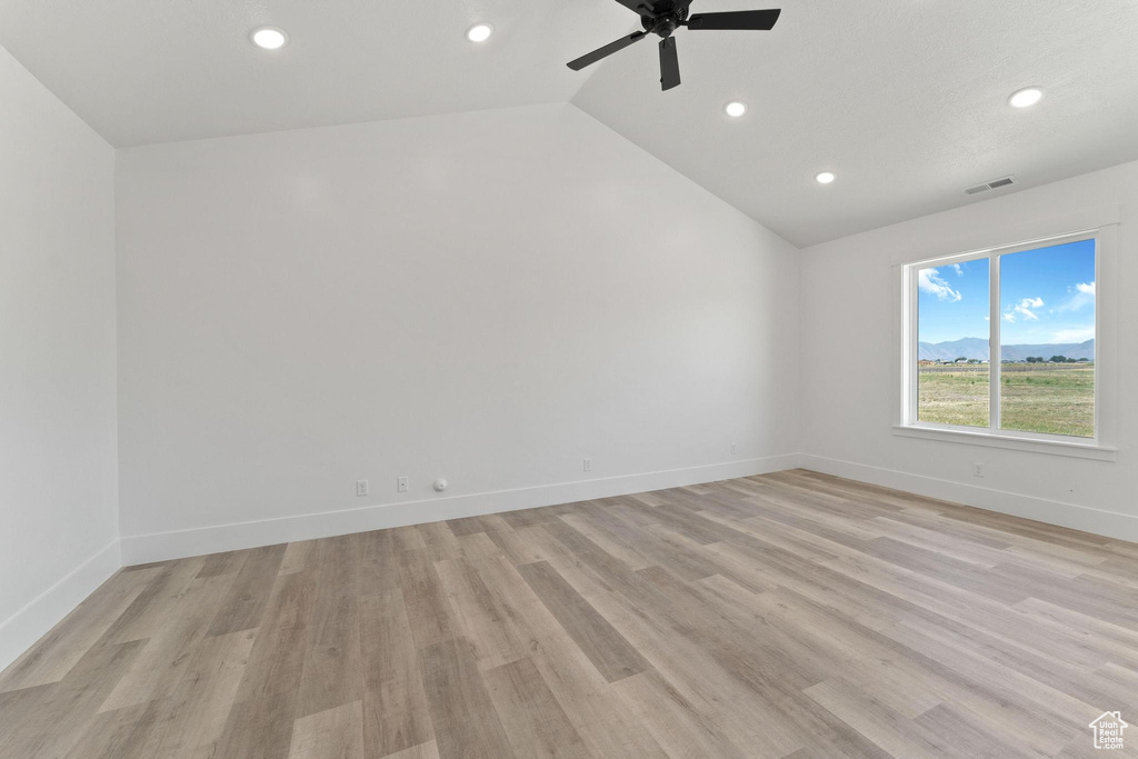 Spare room featuring lofted ceiling, ceiling fan, and light hardwood / wood-style floors