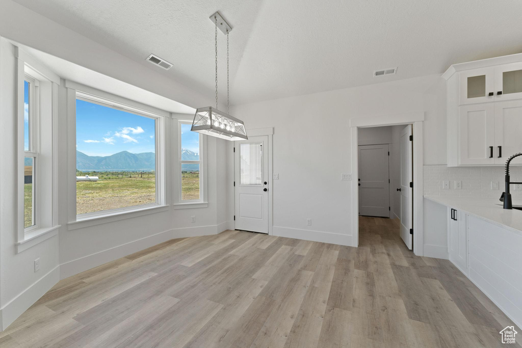 Unfurnished dining area featuring a mountain view and light hardwood / wood-style floors